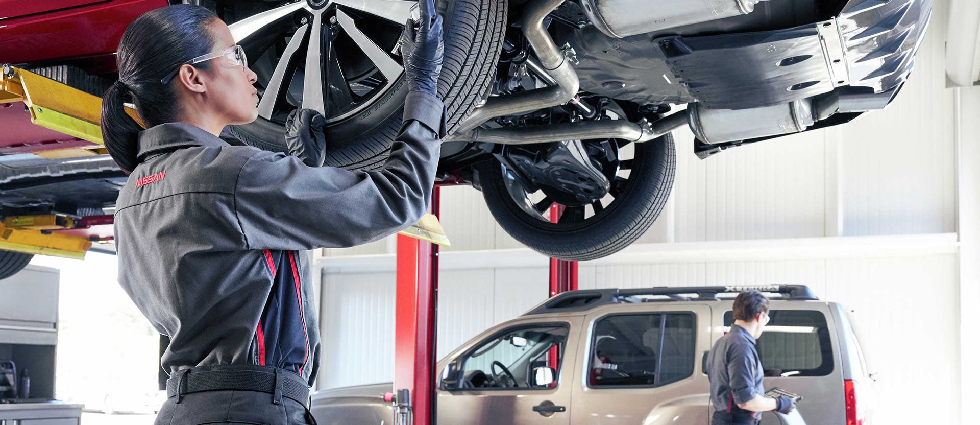 Technician inspecting a vehicle’s undercarriage.