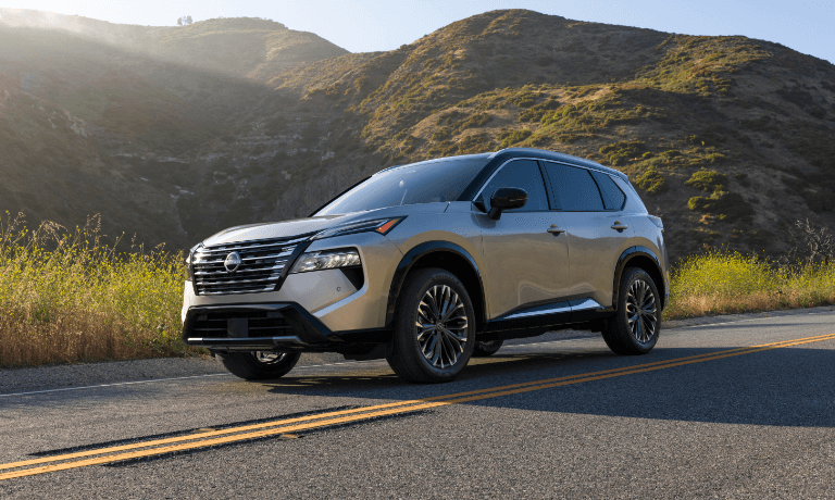 2025 Nissan Rogue driving by grassy hills