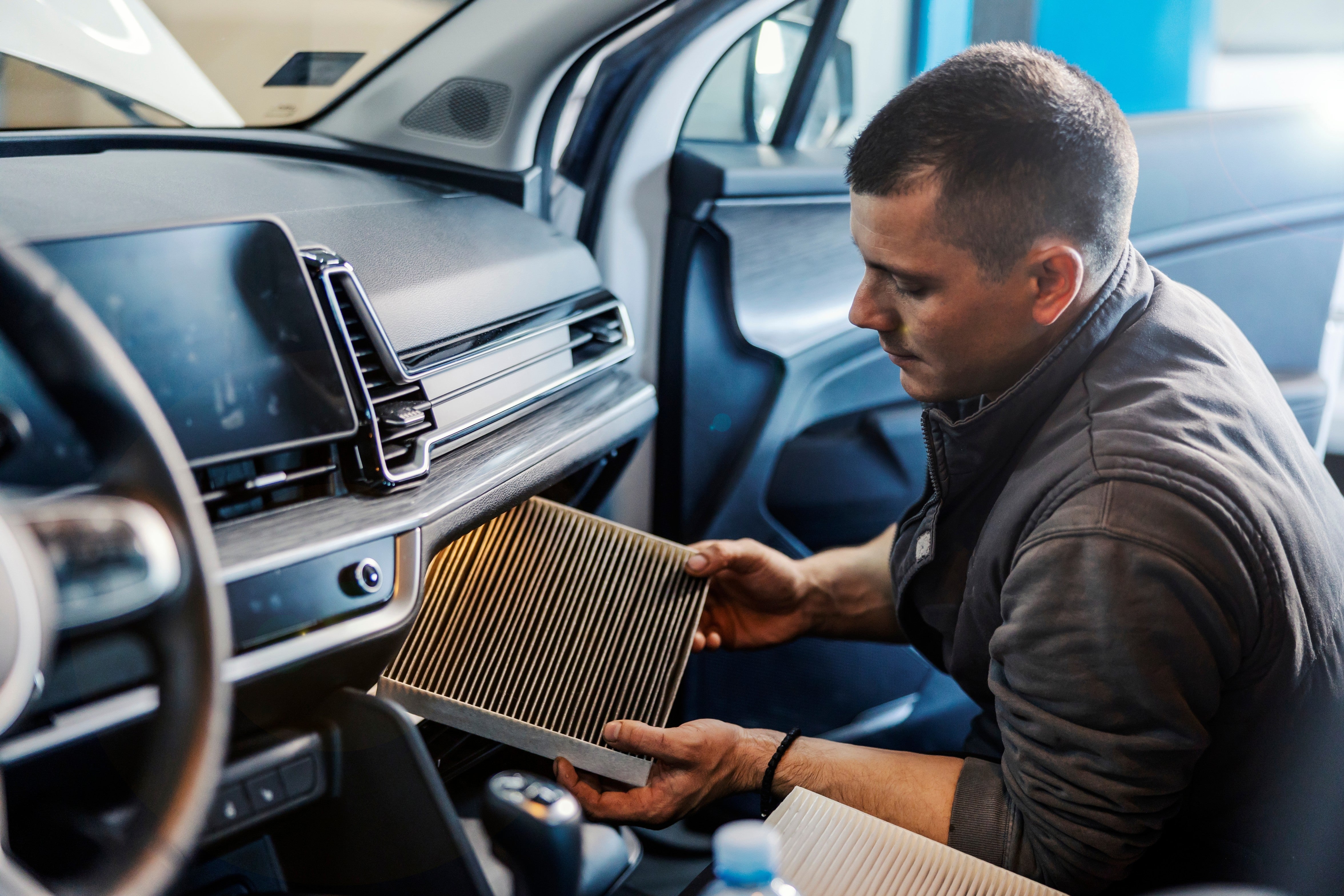 A technician inspects a cabin air filter inside a Nissan vehicle during routine maintenance.